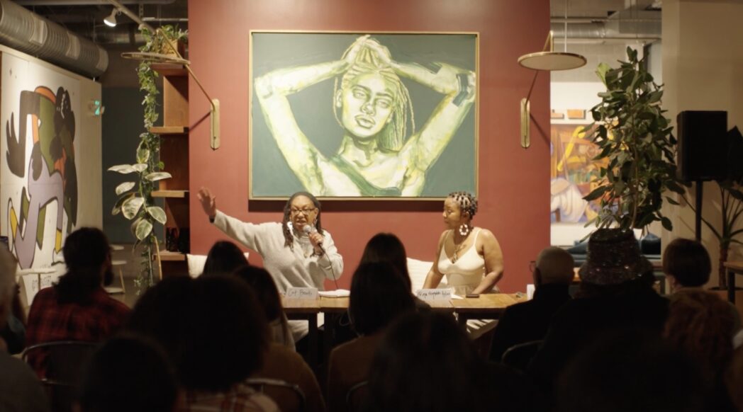 Photo from Wandering Officer panel showing two panelists in front of a crowd.